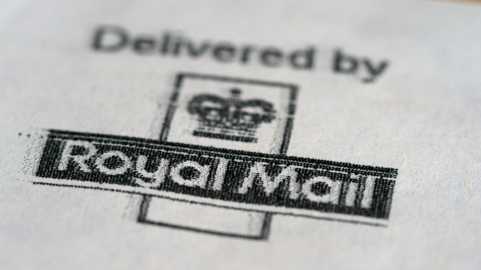 Close-up of a printed Royal Mail logo with crown symbol and text “Delivered by Royal Mail” on white paper.